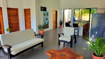 A spacious living area with a sofa, chairs, a coffee table, and a painting on the wall.