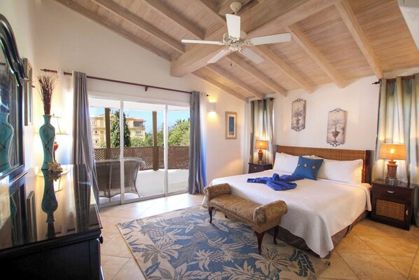 Une chambre d’hôtel avec un lit, une chaise, une table, un ventilateur de plafond et une vue sur l’extérieur.