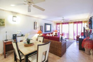 A spacious living area with a dining table, chairs, a red sofa, and a balcony with a view.