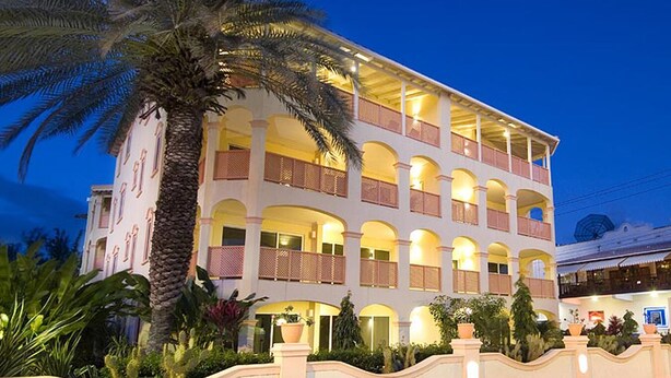 A multi-story hotel with balconies, a palm tree, and a well-lit facade. - 2-bed Apt by Beach in St. Lawrence Gap (Saint Lawrence Gap)