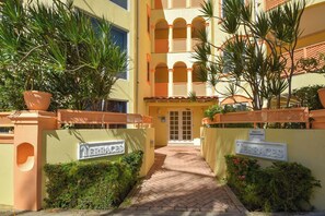 L’entrée d’un hôtel, avec un chemin pavé, une enseigne indiquant « Terrasses » et une autre indiquant « Gestion des installations ».