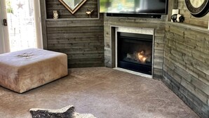 A cozy living room with a fireplace, a television, and a clock on the wall. - Elevate Your Wine Country Escape: Chick-Ranch with Luxurious Amenities, Views, Private Driver (Temecula)