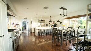 A spacious kitchen with a central island, wooden flooring, and pendant lighting. - Elevate Your Wine Country Escape: Chick-Ranch with Luxurious Amenities, Views, Private Driver (Temecula)