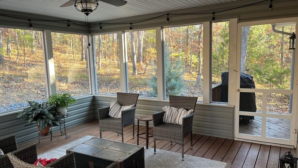 A covered porch with wicker furniture, a ceiling fan, and a view of a wooded area. - GOLFERS GETAWAY (Hot Springs)