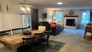 A dining area with a wooden table and chairs, a chandelier, and a fireplace in the background. - GOLFERS GETAWAY (Hot Springs)