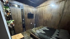 Un dormitorio pequeño con cama, una mesita y una puerta.
