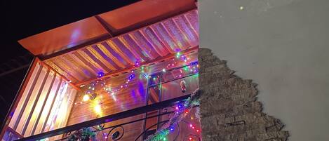 A building with a sloped roof, a wooden interior, and colorful string lights.