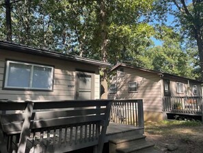 Simple homes with communal living arrangement, surrounded by lush greenery and a peaceful outdoor space.