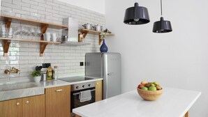 Una cocina moderna con armarios blancos, un refrigerador de acero inoxidable, estantes de madera y un tazón de fruta en la encimera.