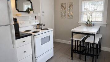 Una cucina con un piano cottura bianco, un forno a microonde e un piccolo tavolo con sedie.
