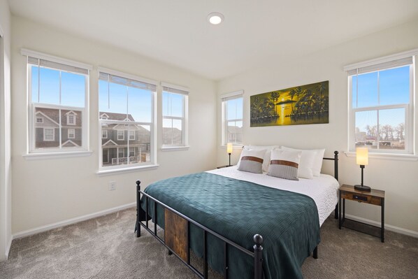 A bedroom with a large bed, two bedside tables, and a painting on the wall.