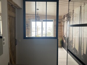 A hallway with a large window, wooden walls, and a ceiling fan. - The Eddy Lodge, a tiny house with a view of nature and a Nordic bath (Neufchâteau)