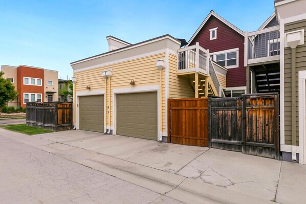 A row of townhouses with attached garages, a wooden fence, and a clear sky.
