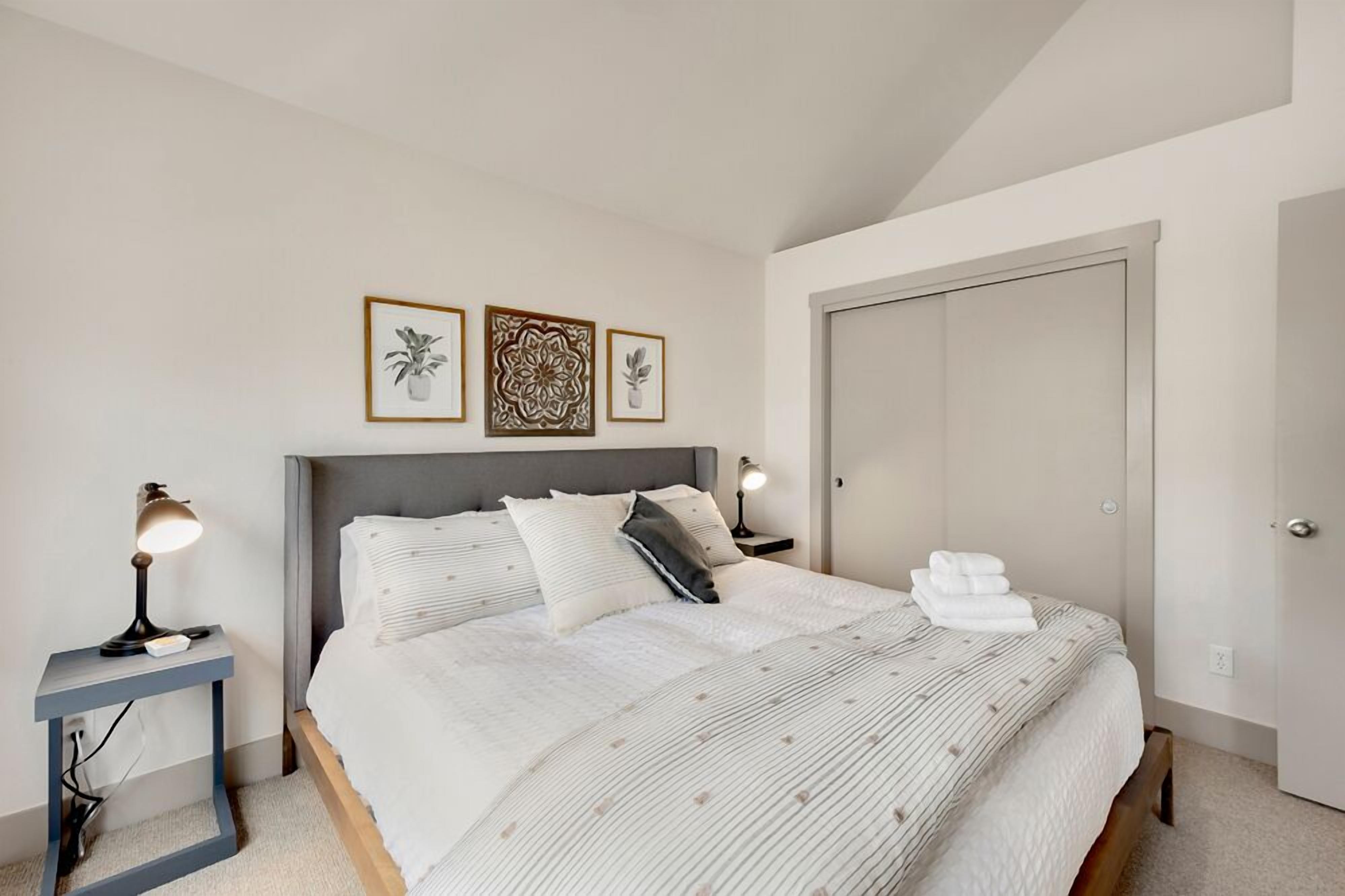 A bedroom with a bed, bedside tables, a nightstand, and a door.