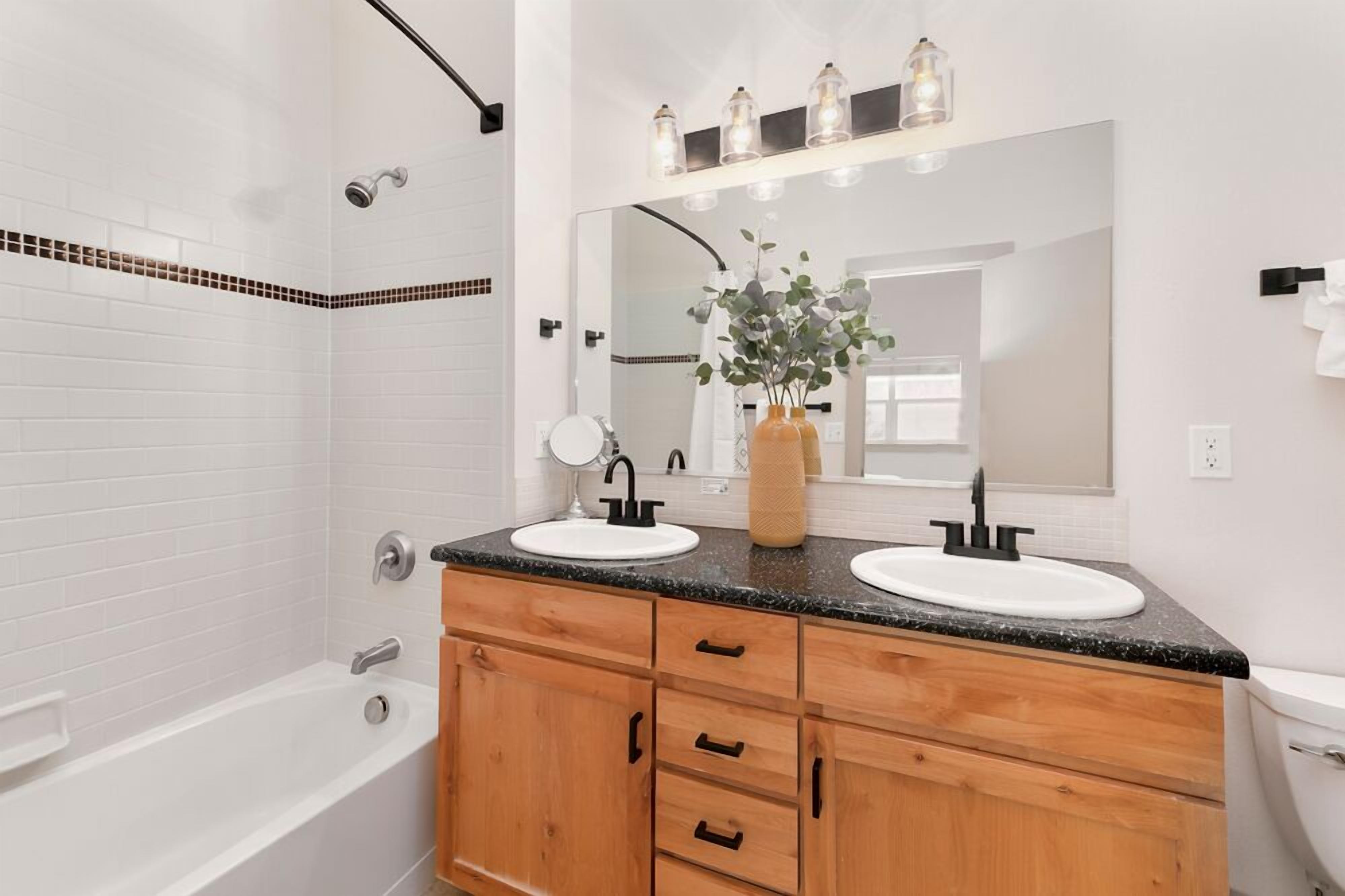 Une salle de bain moderne avec deux vasques, un grand miroir et un meuble-lavabo en bois.