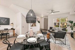 Un comedor moderno con una mesa redonda de vidrio, sillas negras y un jarrón decorativo.