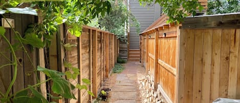 A narrow wooden pathway flanked by wooden fences, leading to a building.