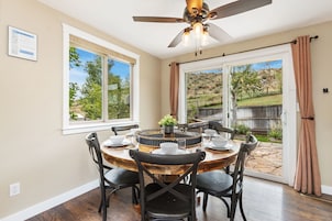A dining area with a round wooden table, black chairs, and a ceiling fan.