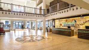 Un hall espacioso con mostrador de recepción, un gran diseño decorativo en el suelo y vistas al mar a través de amplias ventanas.