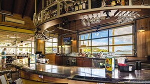 Un bar con mostrador curvo, detalles de madera y un amplio ventanal con vistas al exterior.