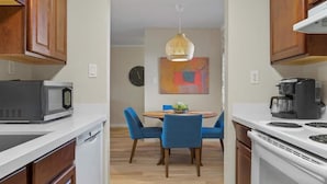 A compact kitchen with a microwave, coffee maker, and a dining area with blue chairs and a table. - Modern and Sophisticated Old Town Scottsdale Gem! (Scottsdale)