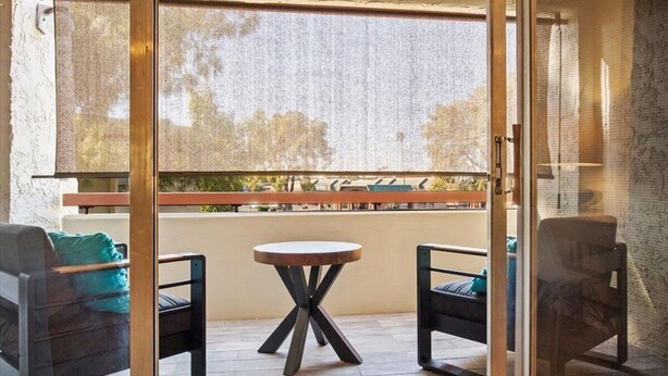 A balcony with a table and two chairs, a view of the outdoors, and a textured wall. - Modern and Sophisticated Old Town Scottsdale Gem! (Scottsdale)