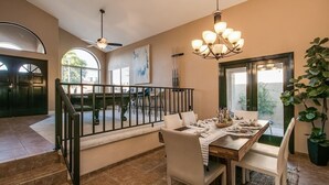 Un vaste espace dédié à la salle à manger, avec une table en bois, des chaises blanches et un lustre.