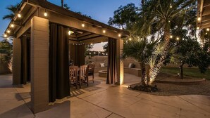 Un espace extérieur aménagé en terrasse, avec une pergola, des sièges et des guirlandes lumineuses.