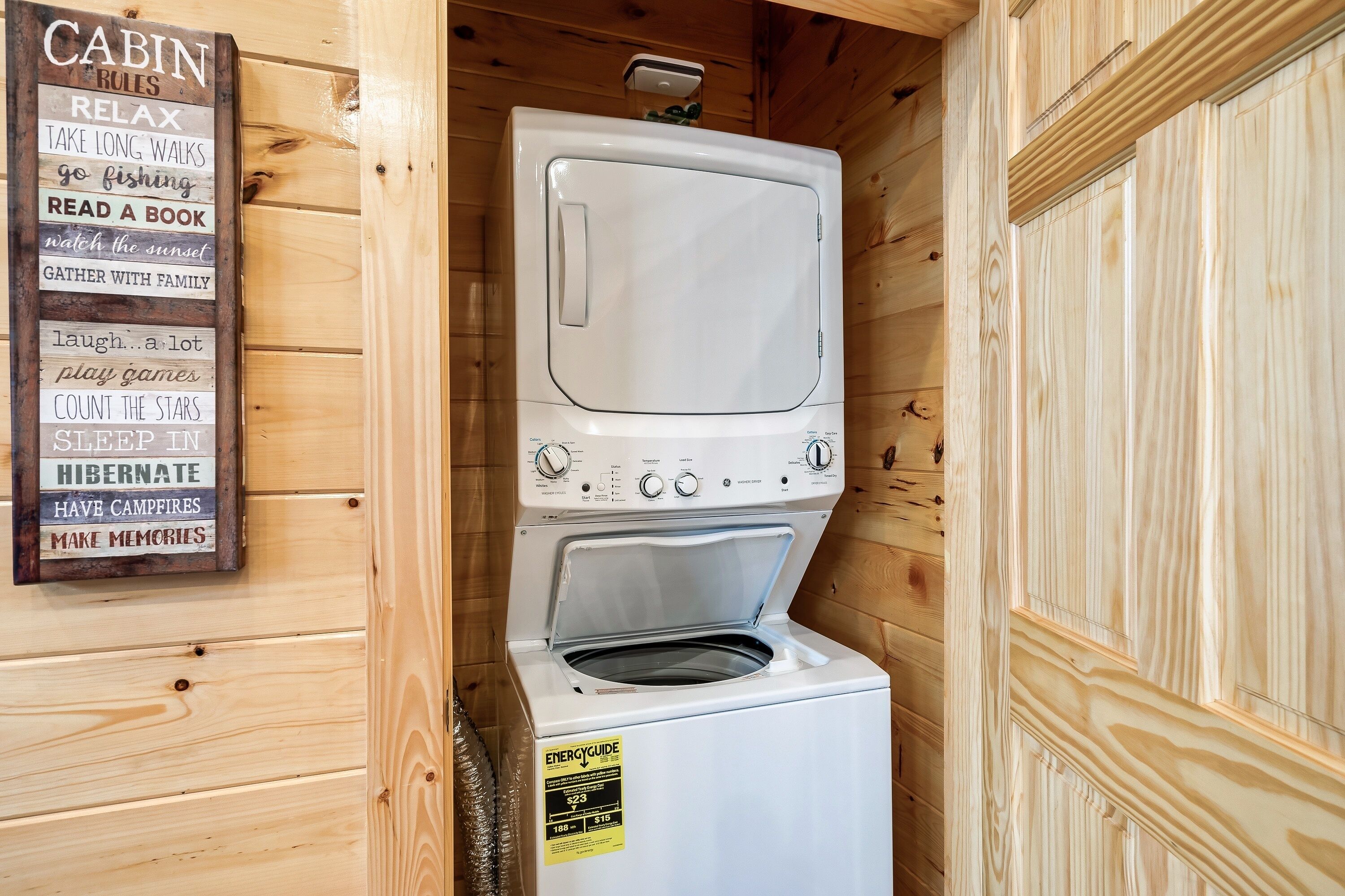 Una cabaña compacta de madera con lavadora y secadora integradas, y un cartel que enumera las normas de la cabaña.