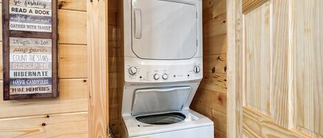 Una cabaña compacta de madera con lavadora y secadora integradas, y un cartel que enumera las normas de la cabaña.