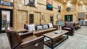 Een gezellig interieur met een houten wand, een bruine leren bank, een bijzettafeltje en een eethoek.