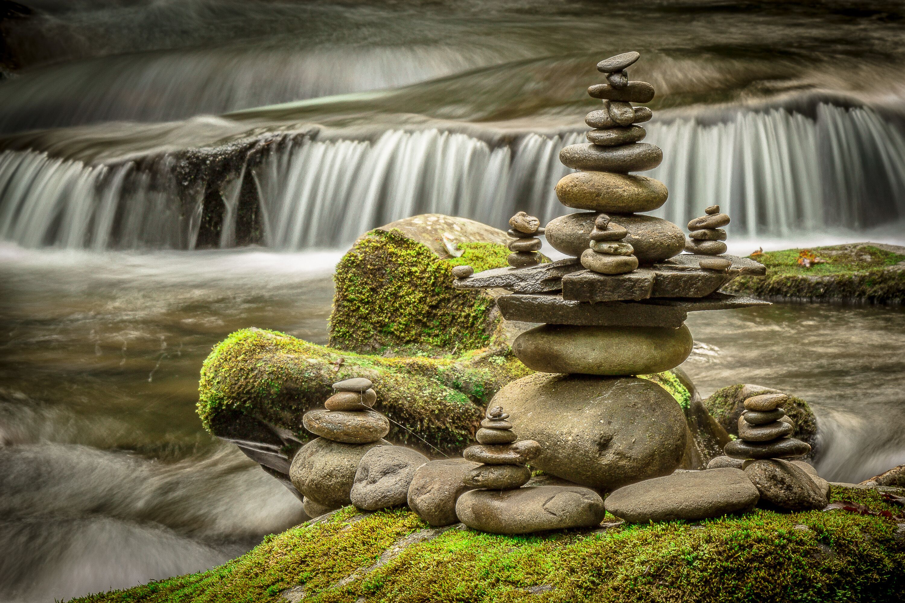 Une cascade paisible, avec un amas de pierres au premier plan.