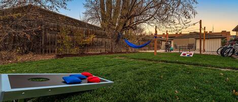 A grassy backyard with a metal table, a hammock, and a barbecue grill.
