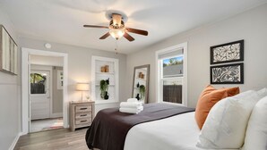 A bedroom with a bed, a ceiling fan, a nightstand, a dresser, and a window with a view. - Charming Old Town Bungalow W/ Free Cruiser Bikes (Fort Collins)