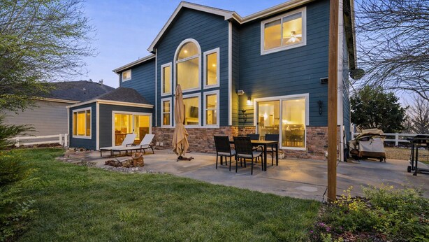 A two-story house with a patio area, outdoor seating, and a garage. - Spacious Home W/ Fun Amenities | Lake & Mtn Views (Loveland)