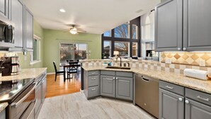 A modern kitchen with grey cabinets, a granite countertop, and a dishwasher. - Spacious Home W/ Fun Amenities | Lake & Mtn Views (Loveland)