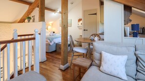 Una habitación acogedora con techo de madera, un sofá, una mesa de comedor y una zona de cocina.
