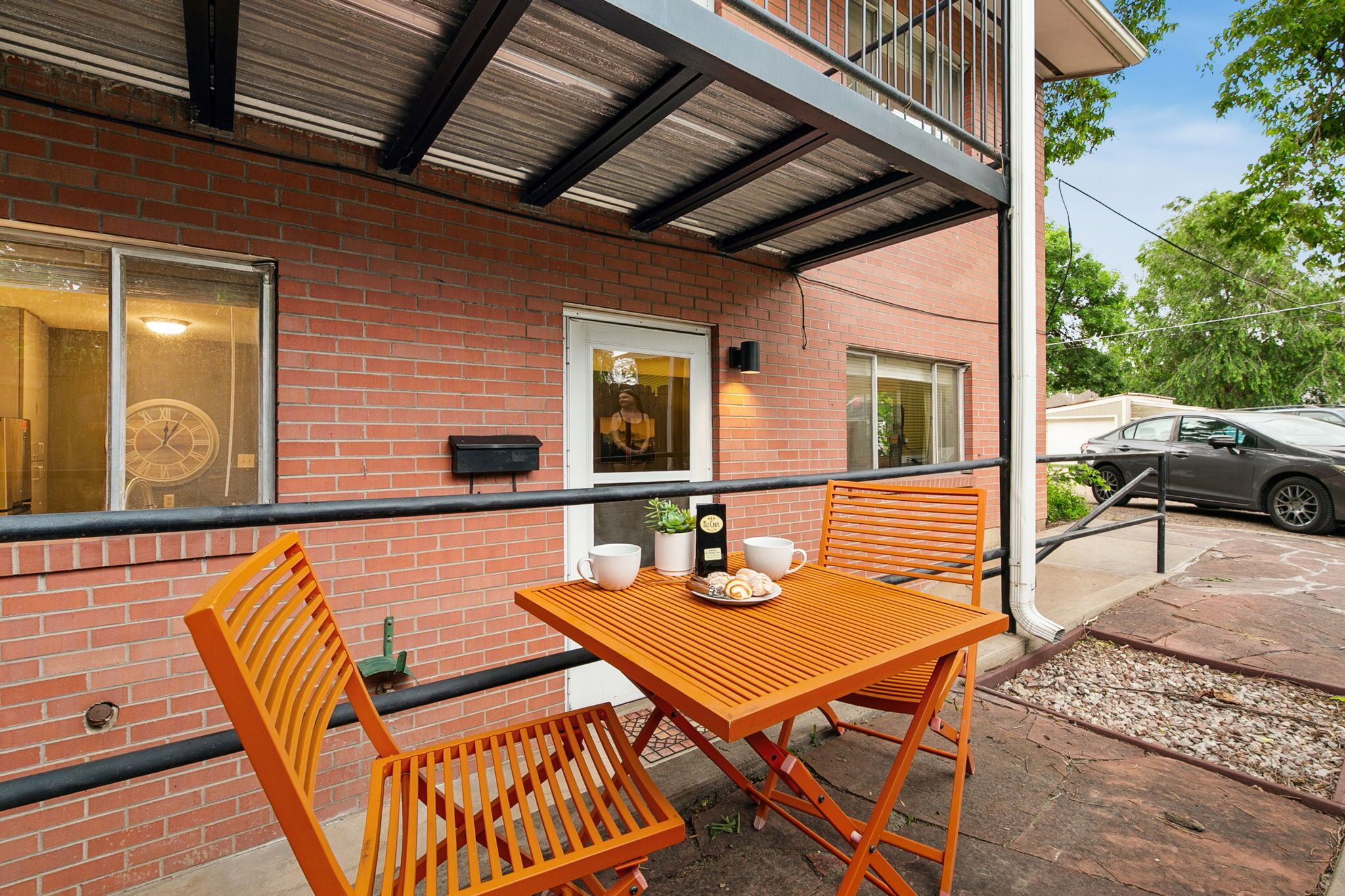 Ein Backsteinhaus mit Balkon, Tisch und Stühlen sowie einer Uhr an der Wand.