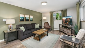 Een woonkamer met een bank, salontafel, televisie en decoratieve objecten.