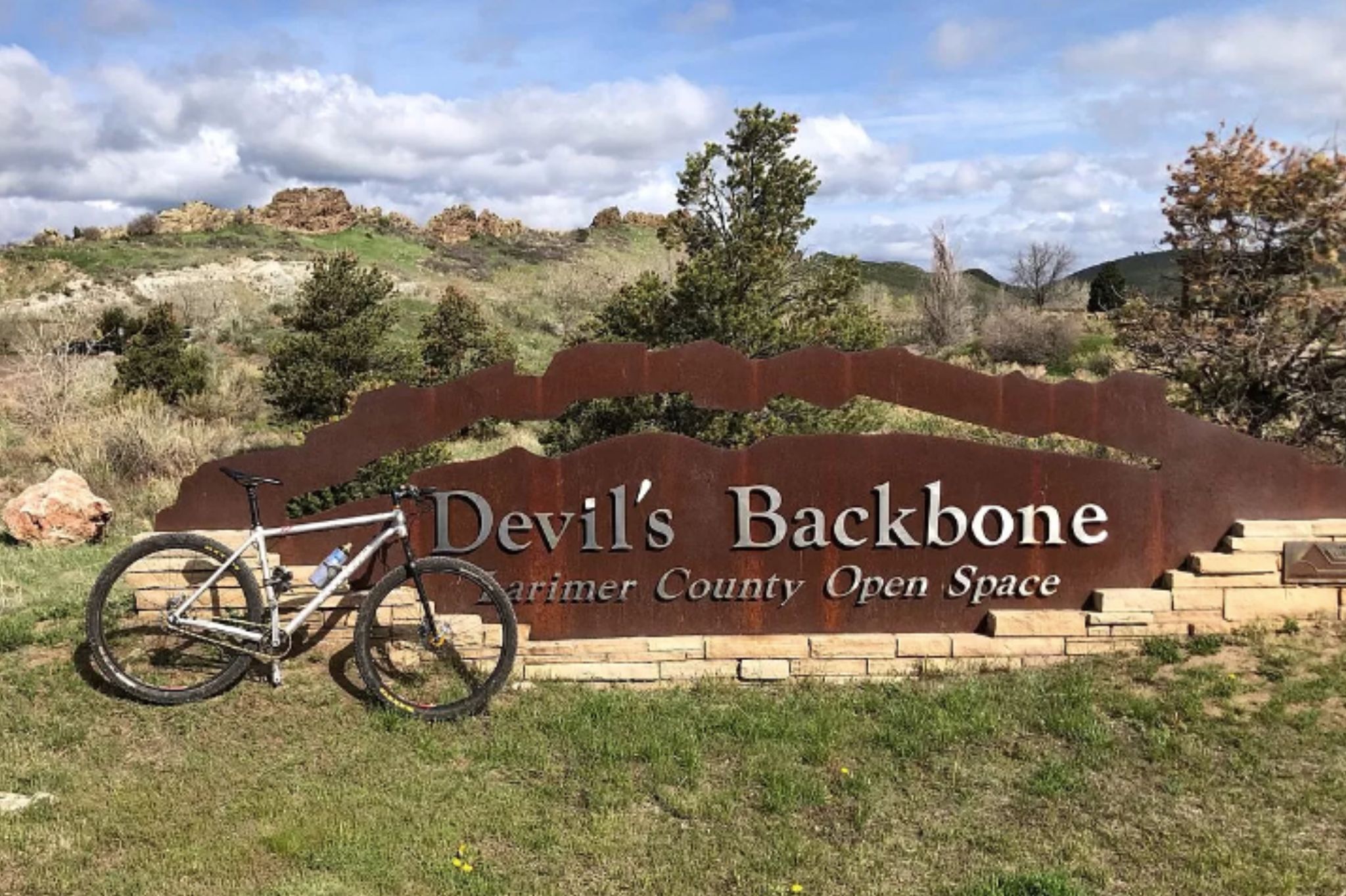 Una bicicleta de montaña estacionada frente a un cartel que dice 'Devil's Backbone, Open Space del Condado de Marin'.