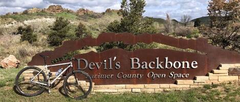 Una bicicleta de montaña estacionada frente a un cartel que dice 'Devil's Backbone, Open Space del Condado de Marin'.