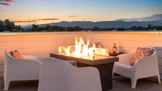 A rooftop terrace with a fire feature, white chairs, and a view of mountains. - Sleek Home Near Old Town W/ Rftp Hot Tub & Mtn Views (Fort Collins)