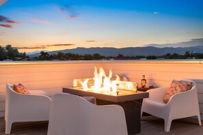 A rooftop terrace with a fire feature, white chairs, and a view of mountains. - Sleek Home Near Old Town W/ Rftp Hot Tub & Mtn Views (Fort Collins)