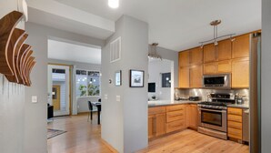 A modern kitchen with wooden cabinets, stainless steel appliances, and a central island. - Sleek Home Near Old Town W/ Rftp Hot Tub & Mtn Views (Fort Collins)