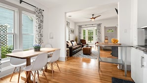 A modern kitchen with a dining area, a living room with a sofa and a coffee table, and a view of the outdoors. - Lola House! Cozy Comfort, Prime Old Town Location (Fort Collins)