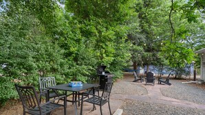 An outdoor patio with a grill, table, and chairs surrounded by dense greenery. - Beautiful Bungalow Next to Csu - Free Cruiser Bikes (Fort Collins)