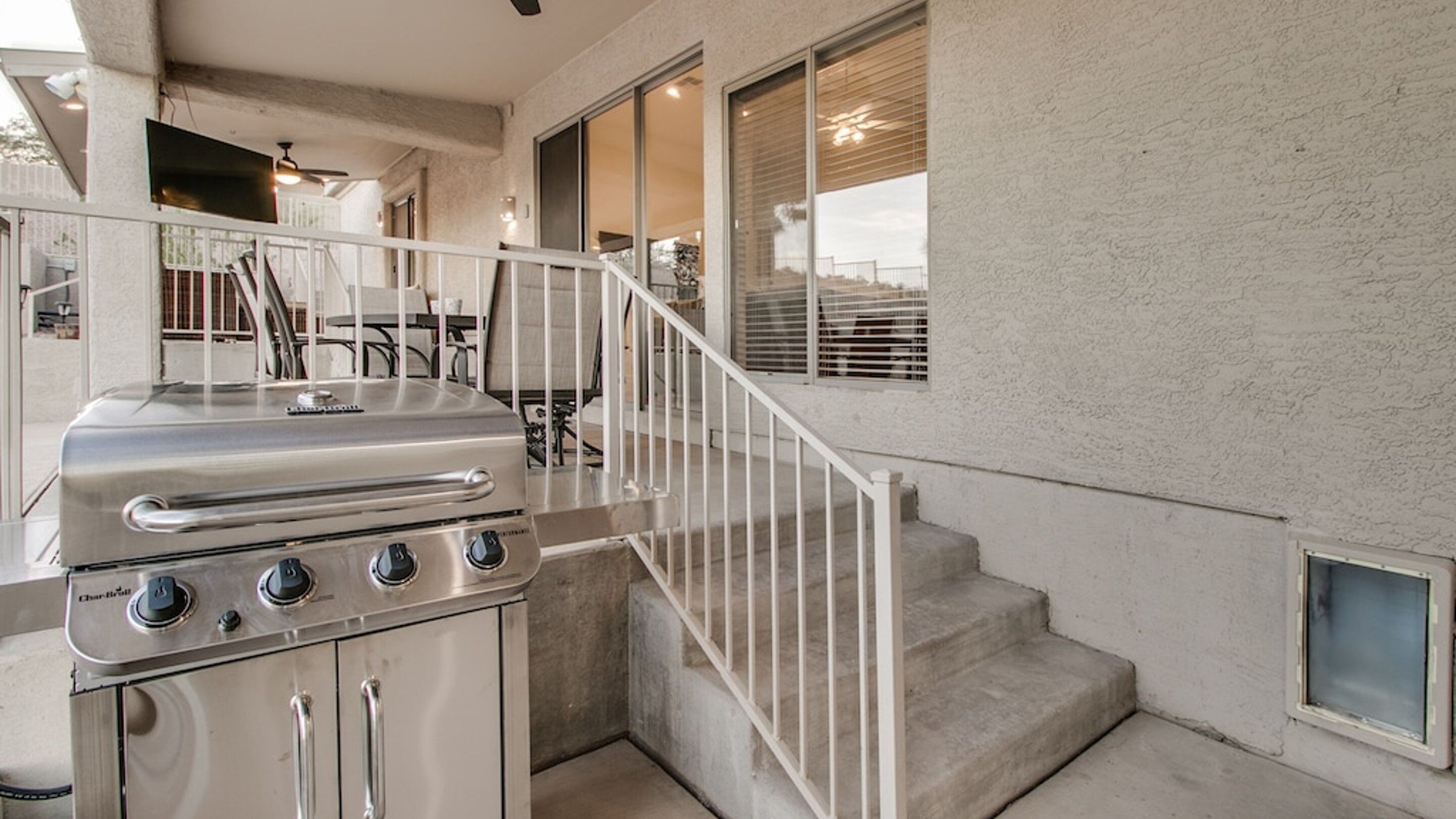 A kitchen with a built-in grill, a staircase, and a view of the outdoors.