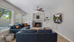 Ein Wohnzimmer mit Kamin, Deckenventilator und Wandfernseher.
