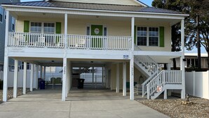 A two-story building with a balcony, a covered entrance, and a staircase leading to the upper floor. - 4 BR, 3 bath Cherry Grove Retreat near CG Pier, Private Pool, 1 block to beach (North Myrtle Beach)
