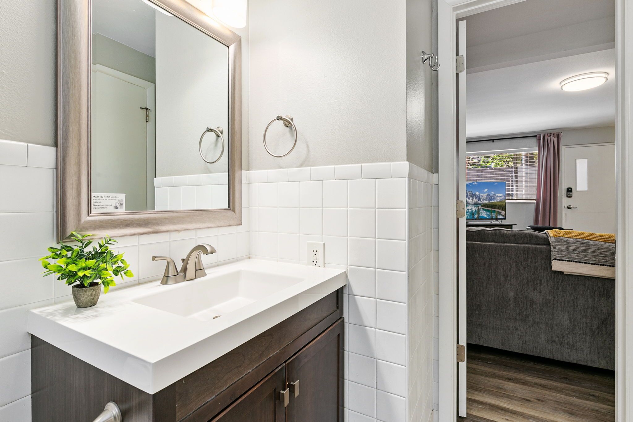 Un baño moderno con un lavabo blanco, muebles oscuros y un espejo grande.